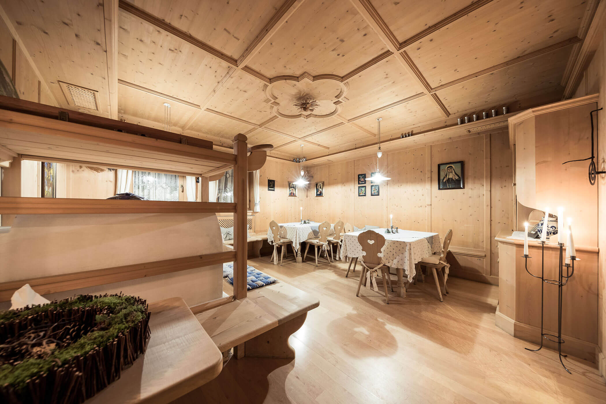 Heller Speisesaal mit Stühlen, Tischen und altem Bauernofen - Hotel Alpenhof