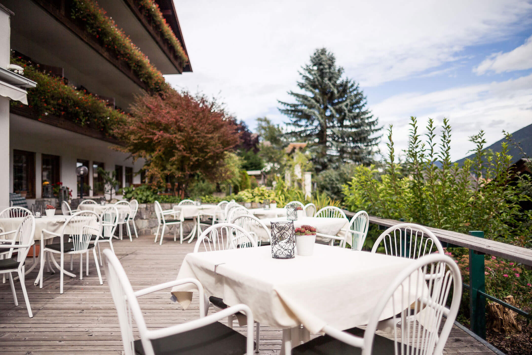 Terrasse des Hotels Alpenhof mit weißen Tischen und Stühlen