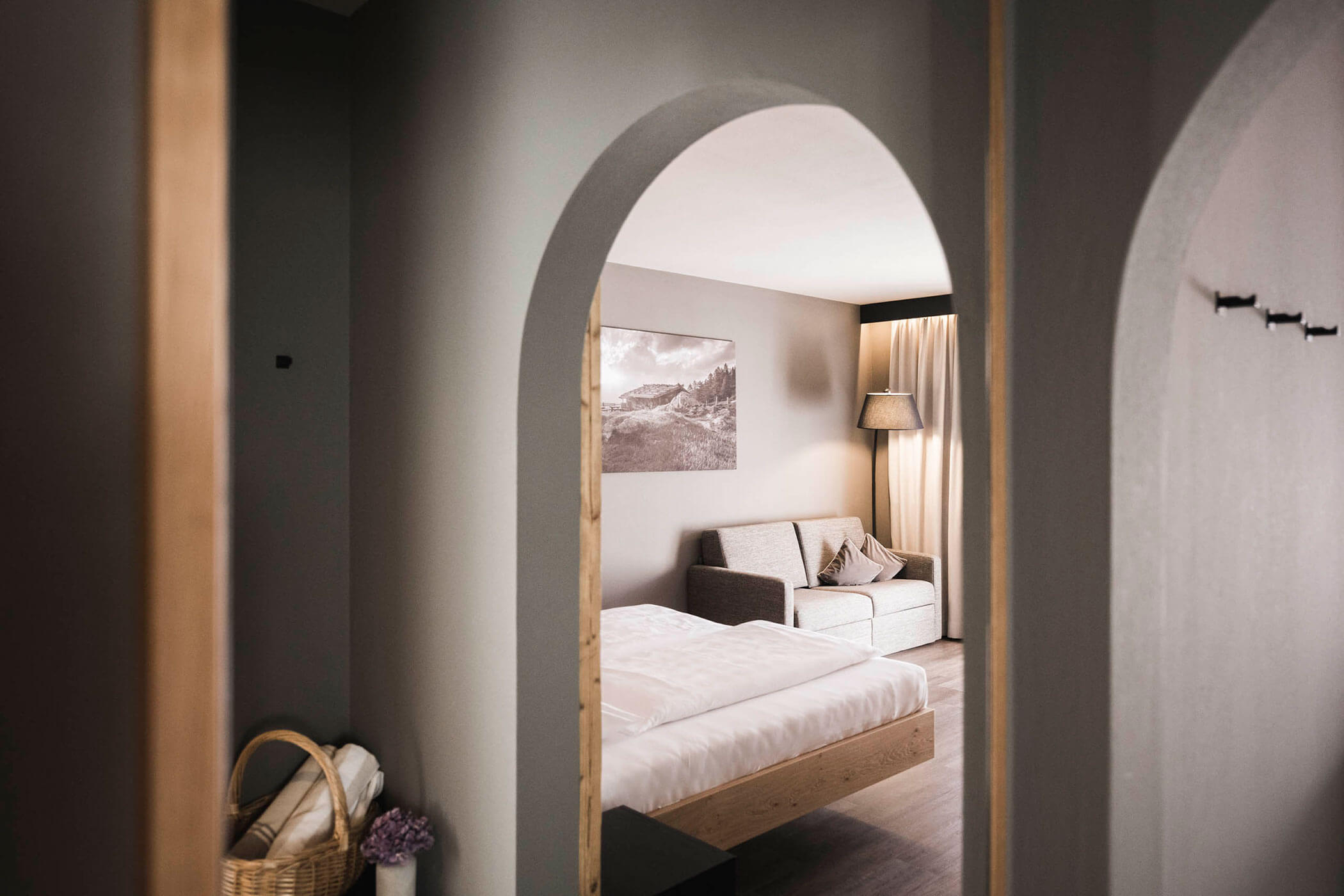 Das Spitzen Zimmer mit Blick auf das Doppelbett und die graue Couch - Hotel Alpenhof